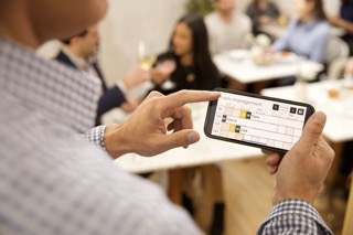 Manager di ristorante che usa Carbonara su un telefono durante il servizio